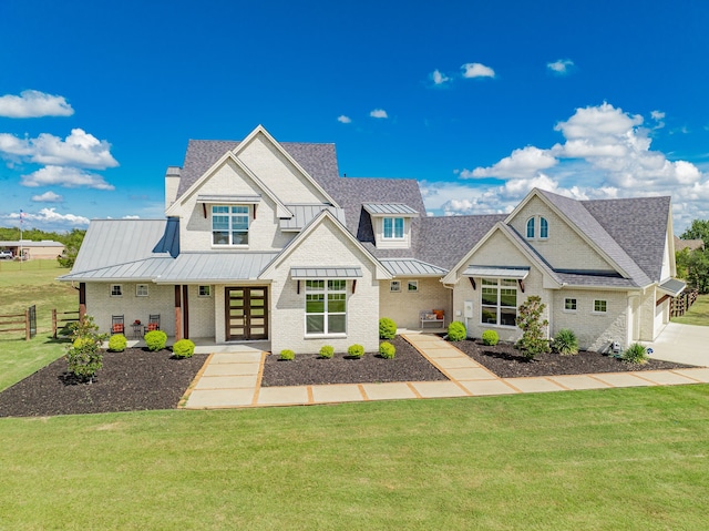 view of front facade featuring fence, a standing seam roof, a front lawn, a garage, and metal roof