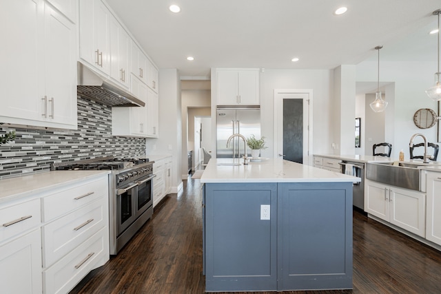 kitchen with dark hardwood / wood-style floors, a center island with sink, hanging light fixtures, sink, and premium appliances