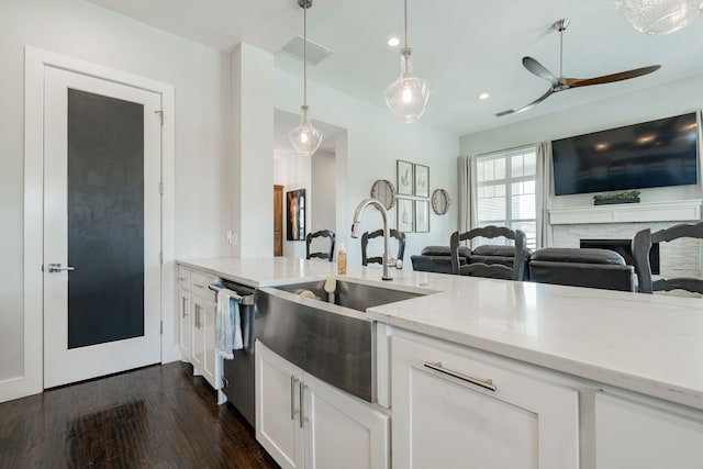 kitchen with a fireplace, pendant lighting, white cabinetry, dark hardwood / wood-style flooring, and ceiling fan