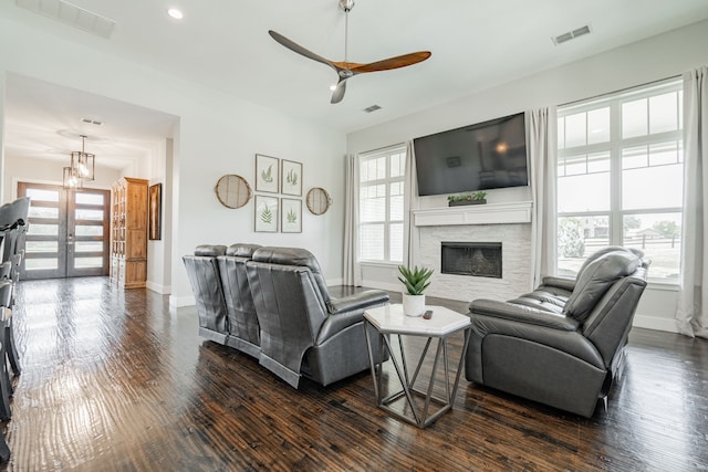 living room featuring ceiling fan with notable chandelier and dark wood-type flooring