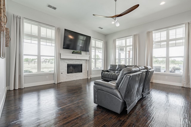 living room featuring a fireplace, dark hardwood / wood-style flooring, and a healthy amount of sunlight