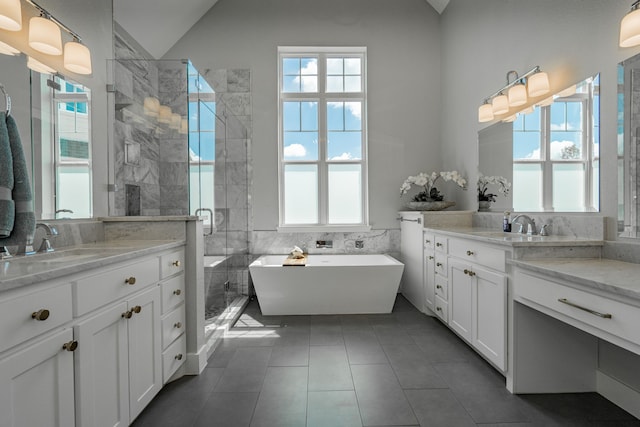 bathroom with vanity, vaulted ceiling, tile patterned flooring, tile walls, and independent shower and bath