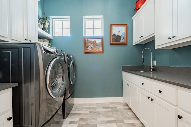 laundry room featuring washing machine and clothes dryer, cabinets, and sink