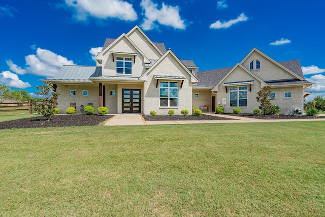 view of front facade with brick siding, a standing seam roof, and a front yard