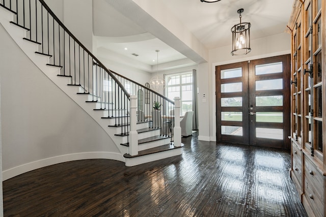 foyer with french doors, dark hardwood / wood-style flooring, and a notable chandelier