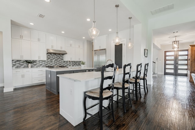 kitchen with dark hardwood / wood-style flooring, stainless steel appliances, white cabinets, and a large island