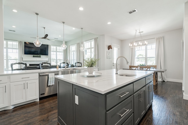 kitchen with dishwasher, light stone counters, sink, dark wood-type flooring, and a center island with sink