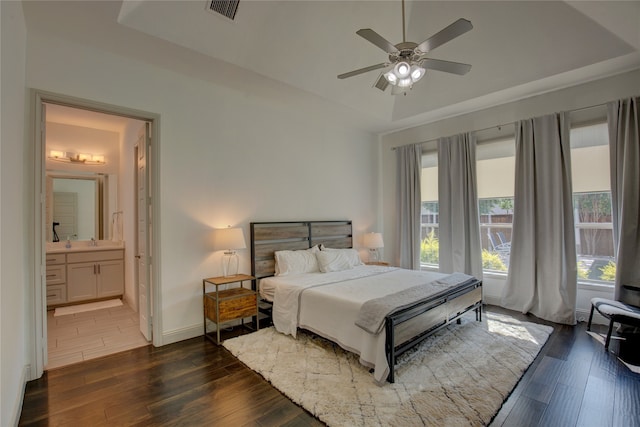 bedroom with connected bathroom, dark wood-type flooring, and ceiling fan