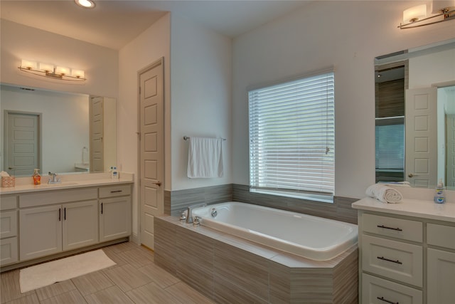 bathroom featuring vanity, a relaxing tiled tub, and toilet