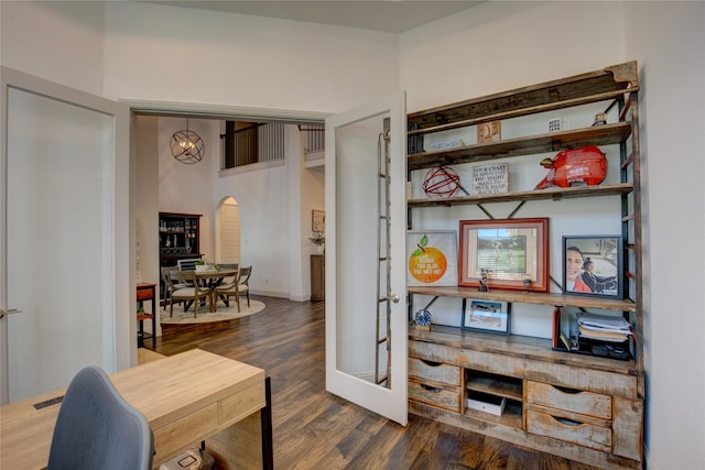 home office with dark hardwood / wood-style floors and an inviting chandelier