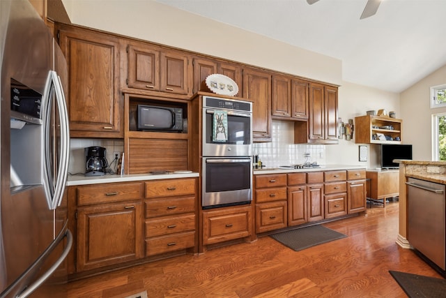 kitchen with backsplash, vaulted ceiling, ceiling fan, dark hardwood / wood-style floors, and appliances with stainless steel finishes