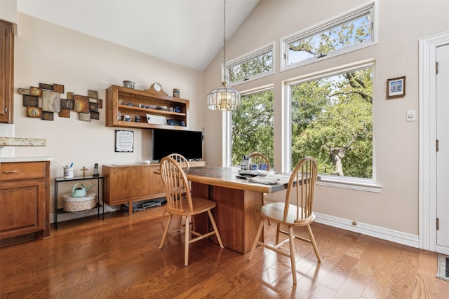 dining space featuring a healthy amount of sunlight, high vaulted ceiling, wood-type flooring, and a chandelier