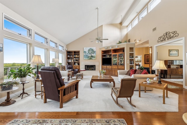 living room with high vaulted ceiling, wood-type flooring, ceiling fan, and a healthy amount of sunlight