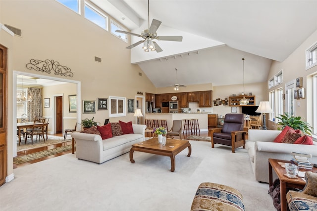 living room with ceiling fan with notable chandelier, high vaulted ceiling, and light carpet