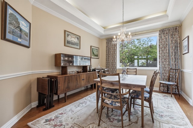 dining space featuring a tray ceiling, crown molding, hardwood / wood-style flooring, and a notable chandelier