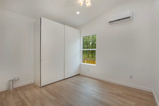 unfurnished bedroom featuring a wall unit AC, ornamental molding, light hardwood / wood-style flooring, ceiling fan, and lofted ceiling