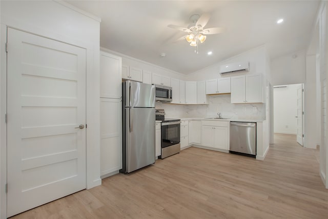 kitchen featuring lofted ceiling, white cabinets, stainless steel appliances, and a wall mounted air conditioner