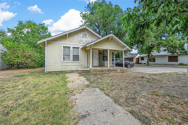 bungalow-style house with a front yard and covered porch