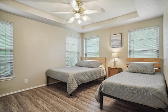 bedroom featuring ceiling fan, dark hardwood / wood-style floors, and a raised ceiling