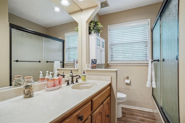 bathroom featuring vanity, toilet, an enclosed shower, and hardwood / wood-style floors