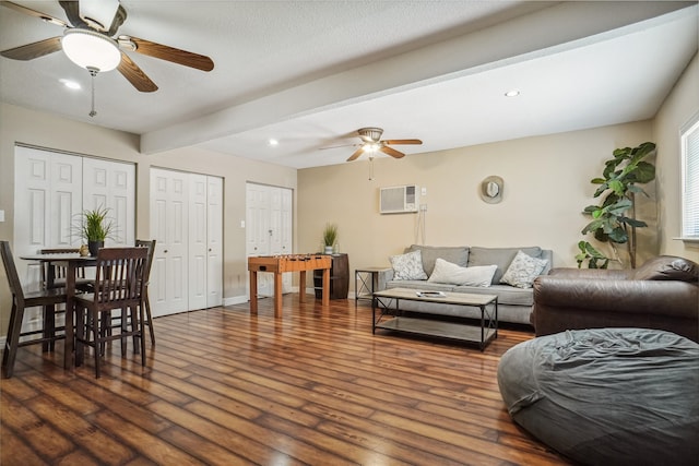 living room with dark hardwood / wood-style flooring, a wall unit AC, ceiling fan, and beamed ceiling