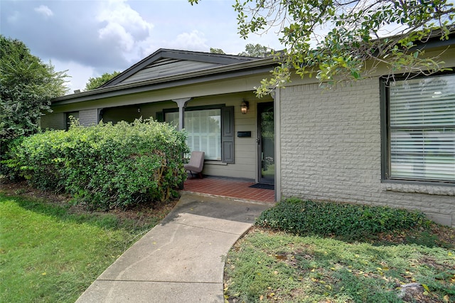 entrance to property featuring a yard and covered porch