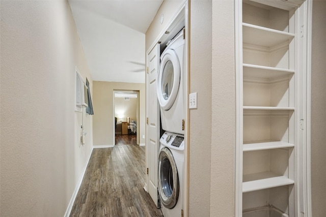 laundry room featuring dark hardwood / wood-style floors and stacked washer / dryer