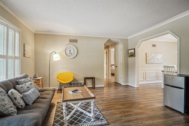 living room featuring crown molding, dark hardwood / wood-style flooring, and a textured ceiling