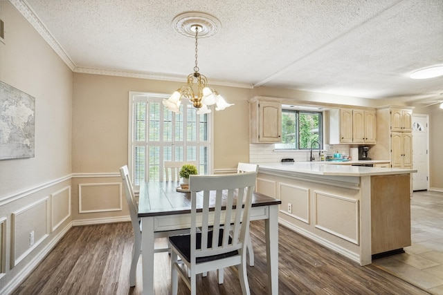 kitchen featuring a textured ceiling, dark hardwood / wood-style floors, decorative light fixtures, an inviting chandelier, and ornamental molding