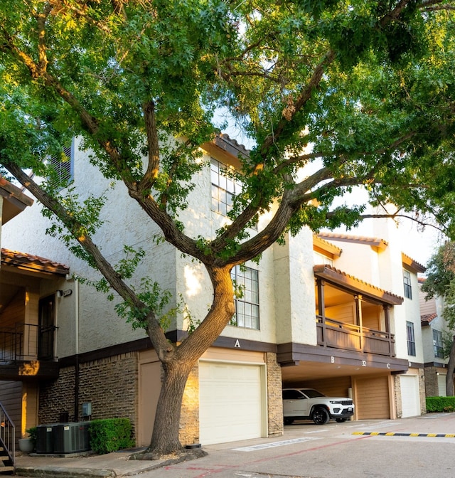 view of front facade featuring a balcony, a garage, and central air condition unit