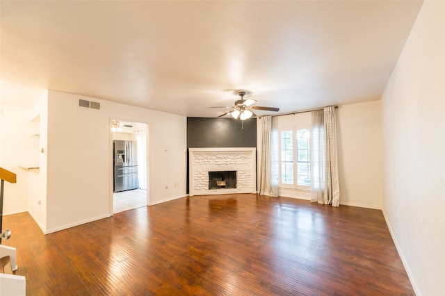 unfurnished living room featuring ceiling fan, a stone fireplace, and wood-type flooring