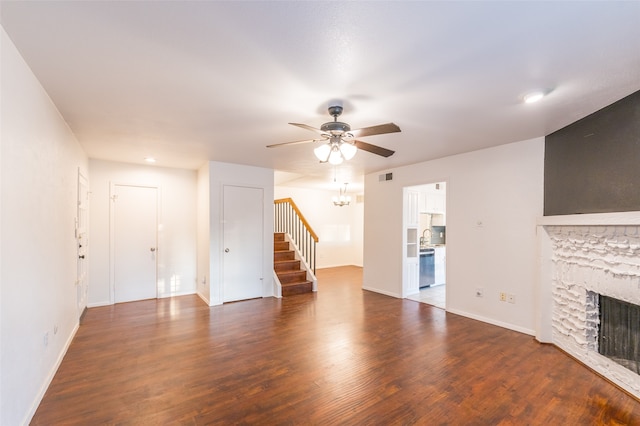 unfurnished living room featuring ceiling fan, a stone fireplace, and dark hardwood / wood-style flooring