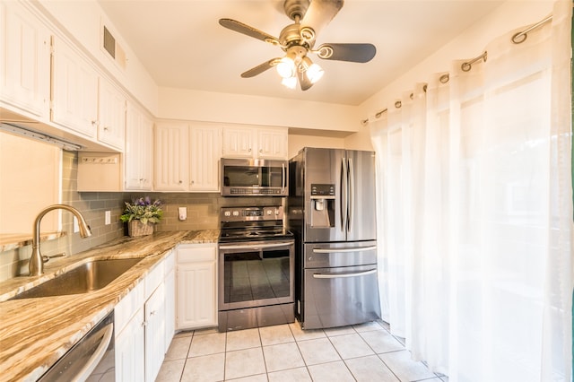 kitchen with decorative backsplash, light tile patterned floors, appliances with stainless steel finishes, white cabinetry, and sink