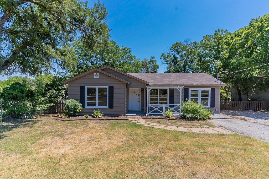 view of front of home with covered porch, fence, and a front lawn