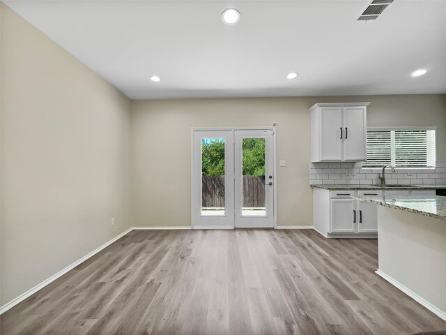 kitchen with white cabinets, light stone countertops, and a wealth of natural light