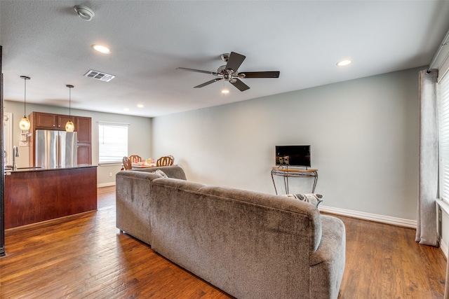 living room with ceiling fan, sink, and dark wood-type flooring