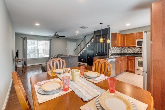 dining area with ceiling fan, light wood-type flooring, and sink