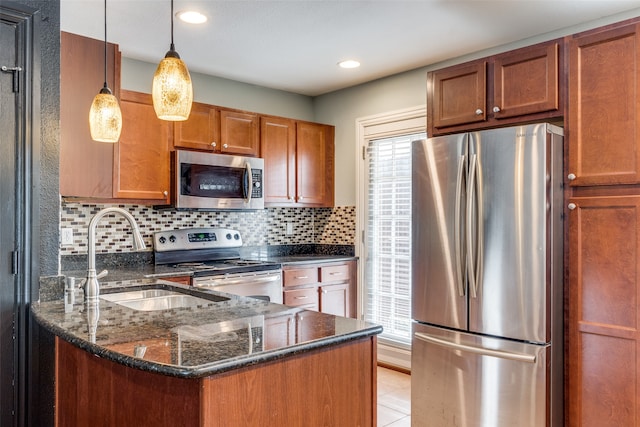 kitchen featuring pendant lighting, backsplash, sink, dark stone countertops, and stainless steel appliances