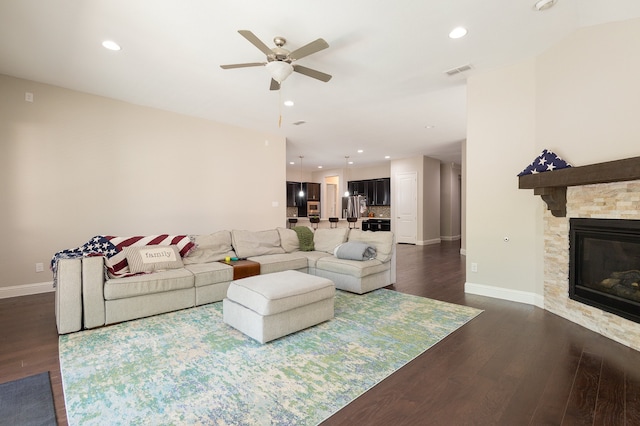 living room with a fireplace, dark hardwood / wood-style flooring, and ceiling fan