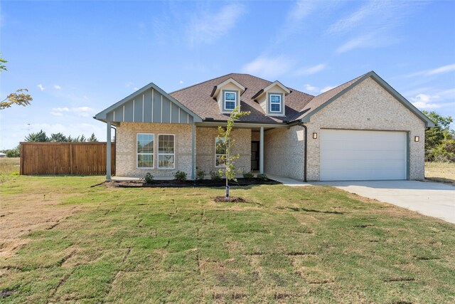 view of front of house with fence, a front yard, brick siding, an attached garage, and driveway