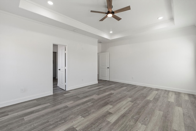 empty room featuring hardwood / wood-style floors, a raised ceiling, ceiling fan, and ornamental molding