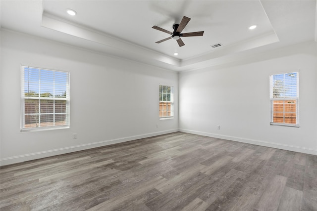 spare room featuring crown molding, a tray ceiling, wood-type flooring, and ceiling fan