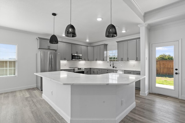 kitchen with gray cabinetry, light stone countertops, stainless steel appliances, pendant lighting, and a kitchen island