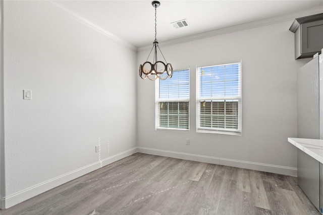 unfurnished dining area featuring an inviting chandelier, light wood-style floors, baseboards, visible vents, and ornamental molding