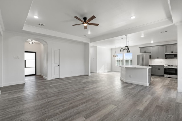 unfurnished living room with dark hardwood / wood-style floors, ceiling fan, a raised ceiling, and ornamental molding