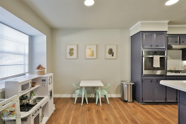 kitchen featuring gray cabinetry, backsplash, crown molding, stainless steel appliances, and light hardwood / wood-style floors