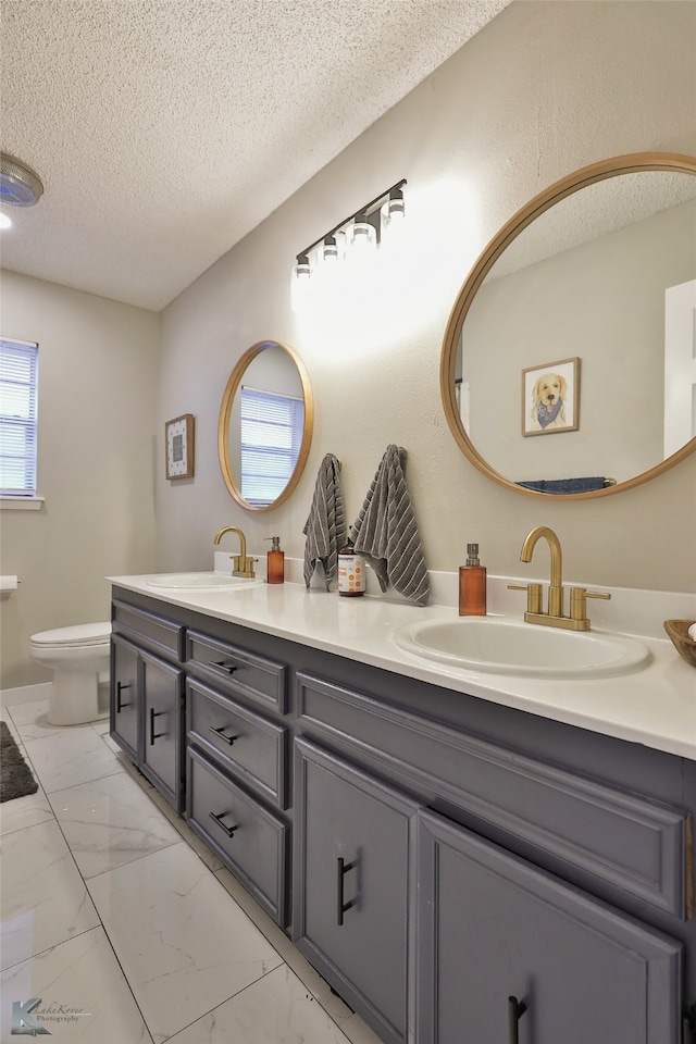 bathroom with vanity, toilet, and a textured ceiling