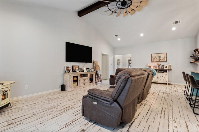 living room with a wood stove, beamed ceiling, high vaulted ceiling, and light hardwood / wood-style floors