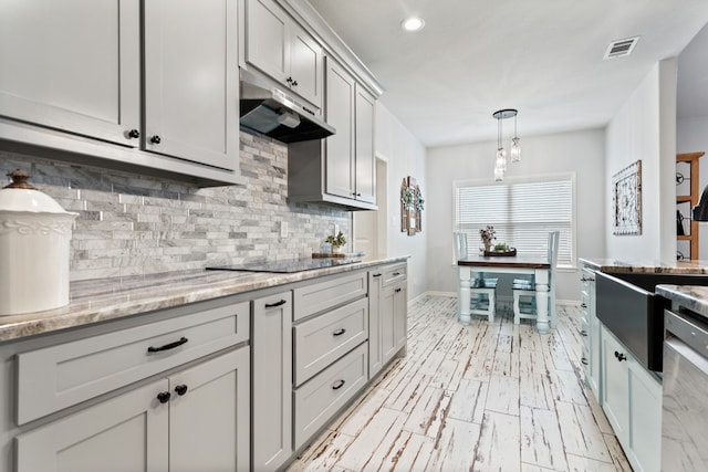 kitchen featuring dishwasher, decorative light fixtures, light stone countertops, black electric cooktop, and tasteful backsplash