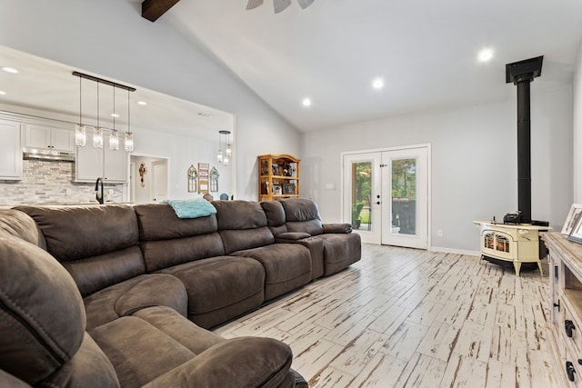 living room featuring high vaulted ceiling, light hardwood / wood-style flooring, a wood stove, french doors, and beam ceiling